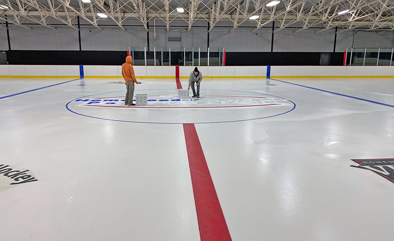 With paint brushes in hand, crews for the Homewood-Flossmoor Park District paint the lines and logos on the NHL-size rink at the H-F Ice Arena. After 15 months of a major rebuild, the rink will officially reopen March 12. (Provided photo/H-F Park District)