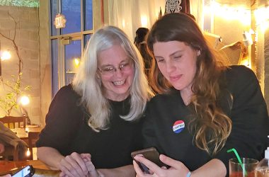 Homewood trustee candidate Anne Colton, left, looks on as Sarah Meeks checks election results on her phone during a results watching party at Rabid Brewing on Tuesday evening. (Eric Crump/H-F Chronicle)