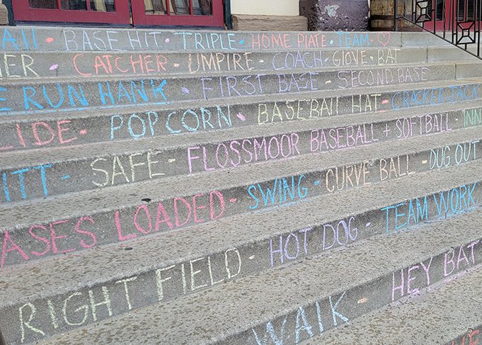 Local businesses help cheer on youth ballplayers prior to opening day ceremonies. Some decorated their display windows, but in the case of Flossmoor Station Restaurant and Brewery, the steps leading to the front door are chalked in a baseball theme. (Eric Crump/H-F Chronicle)