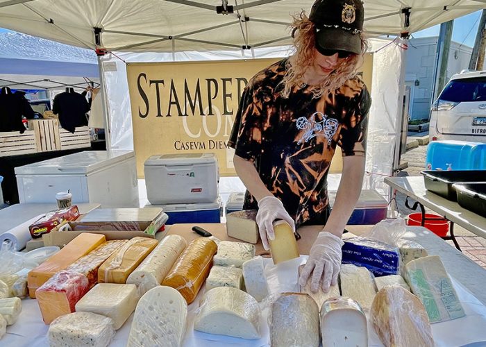 Eli Fredenburg of Stamper Cheese prepares his display. Stamper is a perennial participant at Homewood's Farmers Market, and it is Fredenburg's third year sharing Stamper's cheeses. (Randall Weissman/H-F Chronicle)