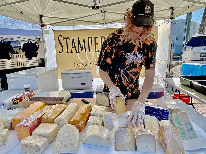 Eli Fredenburg of Stamper Cheese prepares his display. Stamper is a perennial participant at Homewood's Farmers Market, and it is Fredenburg's third year sharing Stamper's cheeses. (Randall Weissman/H-F Chronicle)