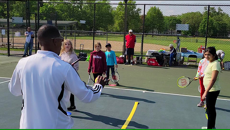Tennis coach John Morris explains basics of the game to young players Saturday, May 20, at the USTA tennis introduction event in Flossmoor. (Eric Crump/H-F Chronicle)