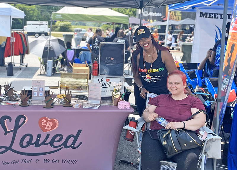 2BLoved owner Ashley McGee, standing, with a community member at HF Juneteenth Festival on June 17. (Nuha Abdessalam/H-F Chronicle)