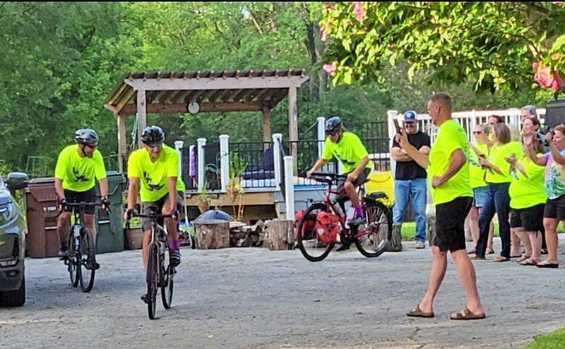 Cyclists, from left, Greg Castady, Dana Noble and Chris Dedo head down the driveway to start their 130-mile trek for Jackie's Warriors, a foundation that raises funds for dementia support, while Nate Olson records the moment and supporters cheer them on. (Eric Crump/H-F Chronicle)