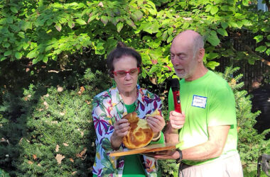 Gloria Lippert breaks bread as part of the Sukkot ceremony while her husband, Jeffery Lippert, speaks to the diverse group of friends and family at the event Oct. 1 in Flossmoor.