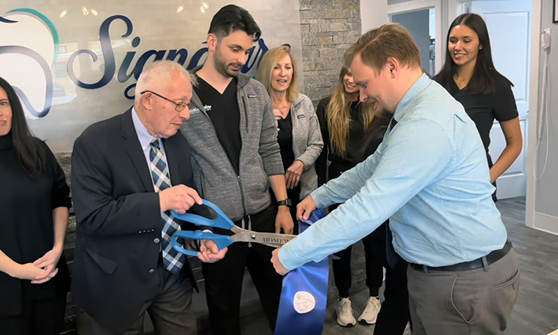 Homewood Mayor Rich Hofeld, left, cuts souvenir pieces while Assistant Village Manager Tyler Hall holds the ribbon and Dr. Alex Shore looks on. (Nick Ulanowski/H-F Chronicle)