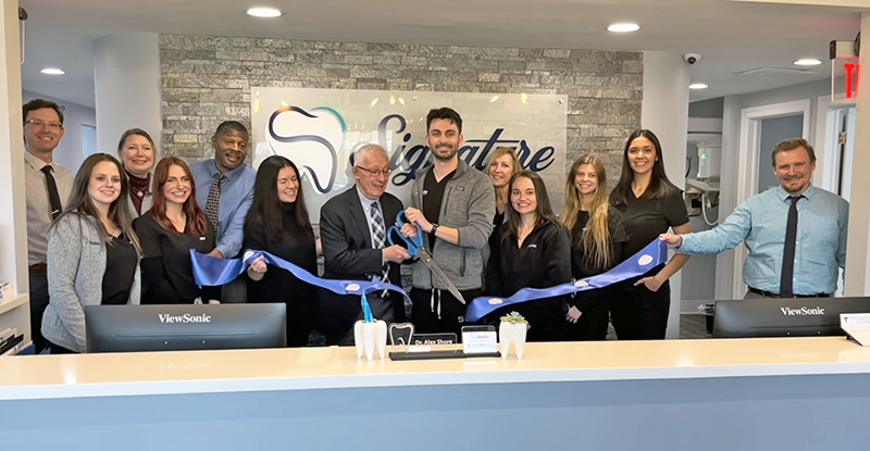 Homewood Mayor Rich Hofeld, left, cuts the blue ribbon with Dr. Alex Shore at Signature Smile Arts grand opening celebration. (Nick Ulanowski/H-F Chronicle)