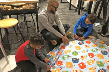 Dad Lorenzo Gholston works with his sons Colin, left, and Ellin, right, on a blanket project for the Martin Luther King Day of Service project. (Marilyn Thomas/H-F Chronicle)