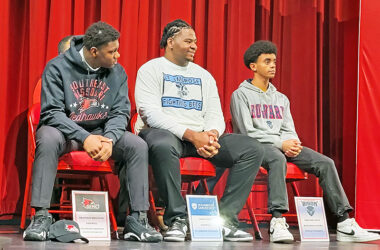 Football players Brandon Brigham (left), Jalen Cole and runner Habtamu Epley wait for the start of Homewood-Flossmoor's college signing day event Tuesday. (David P. Funk/H-F Chronicle)