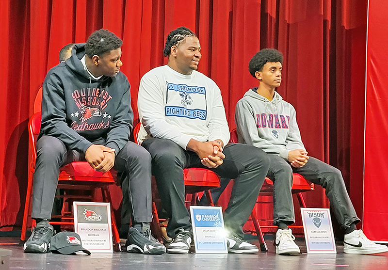 Football players Brandon Brigham (left), Jalen Cole and runner Habtamu Epley wait for the start of Homewood-Flossmoor's college signing day event Tuesday. (David P. Funk/H-F Chronicle)