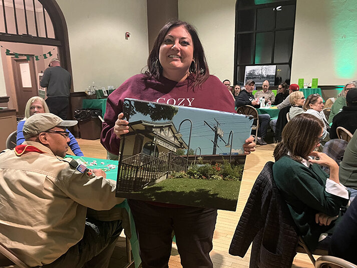 Stephanie Oliver shows off the painting of Flossmoor Station that she won in the raffle. (Nick Ulanowski/H-F Chronicle)