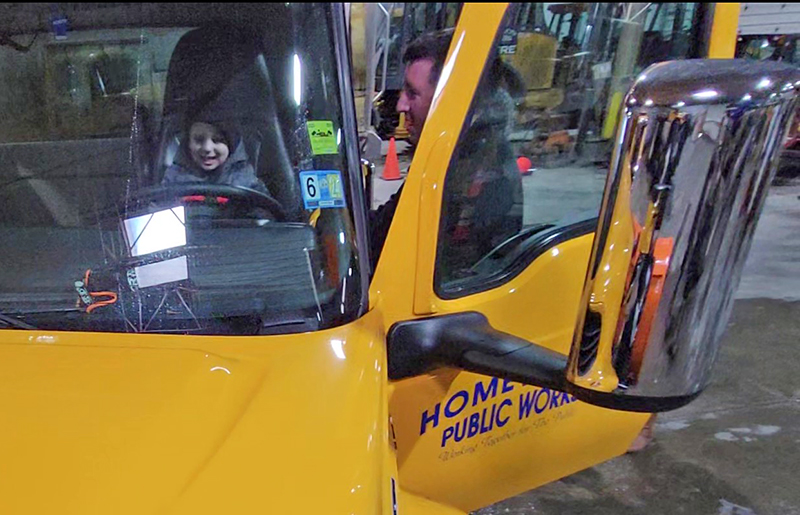 Nic Cortellini, right, helps his son, Gavin, pretend to drive the Blizzard Wizard snowplow. (Eric Crump/H-F Chronicle)