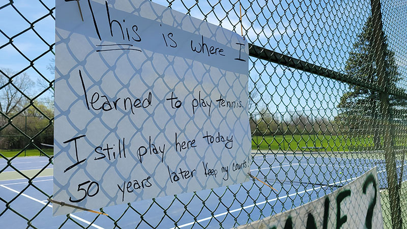 A sign on the fence of the tennis courts near Heather Hill School appeals to village officials to save the courts. (Eric Crump/H-F Chronicle)
