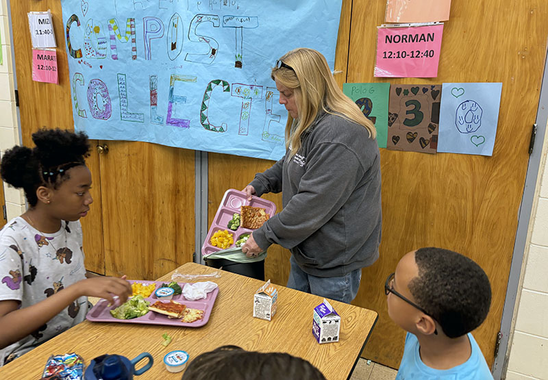 Parent volunteer Patty Welsh collects lunch cast-offs for the composting project at Churchill School. (Marilyn Thomas/H-F Chronicle)