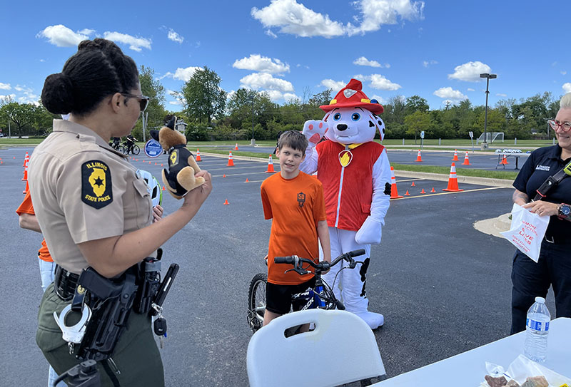 Illinois State Trooper Genelle Jones, left, Michael and Paw Patrol's Firefighter Marshall at Parker Junior High for the Flossmoor Bike Rodeo on May 11. (Nuha Abdessalam/H-F Chronicle)