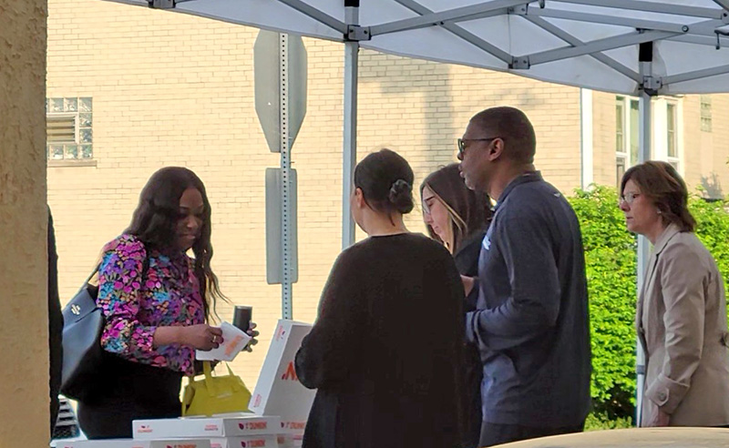 A commuter, left, gets a free donut from Homewood village staff members Antonia Steinmiller, Amy Zukowski, Napoleon Haney and Nancy Allen. (Eric Crump/H-F Chronicle)