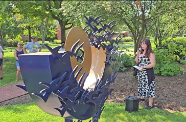 Flossmoor Public Art Commission member Jodie Lawrence introduces "Reaching for the Sky," a sculpture by Hilde DeBruyne, during the commission's 2024 walking tour. (Chronicle file photo)