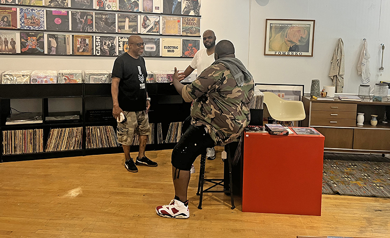 DJ 5ifth Element, far right, chatting with a customer and co-owner Tony Fields, left, at Conservatory Vintage and Vinyl. (Nick Ulanowski/H-F Chronicle)