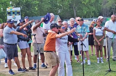 Michael Svetlic, in the orange shirt, and his daughter, Flossmoor Mayor Michelle Nelson, lead local elected officials and the crowd in the singing of "Take Me Out to the Ballgame." (Eric Crump/H-F Chronicle)