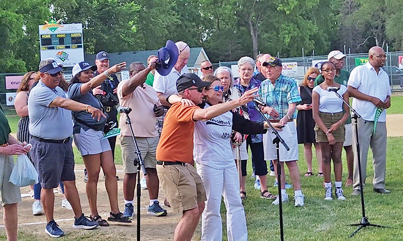 Michael Svetlic, in the orange shirt, and his daughter, Flossmoor Mayor Michelle Nelson, lead local elected officials and the crowd in the singing of "Take Me Out to the Ballgame." (Eric Crump/H-F Chronicle)