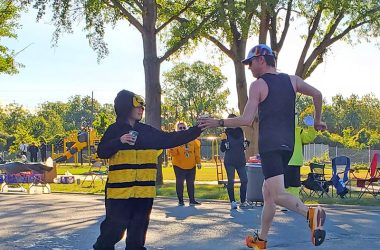 Zach Humm hands Gatorade to a passing runner at the Hidden Gem's Heather Hill water station. (Chris Weber/H-F Chronicle)