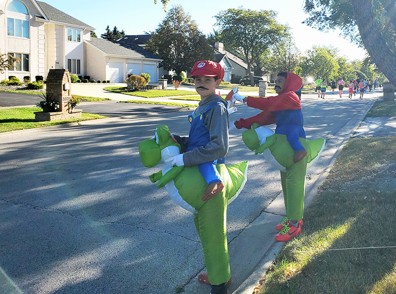 Max Rudolph and Avery Orr ride on their Yoshis while cheering on runners. (Chris Weber/H-F Chronicle)