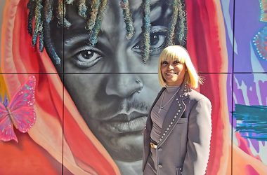 Homewood Brewing CEO Carmela Wallace poses in front of the mural by Corey Pane of her late son, Jarad Higgins, aka Juice WRLD. (Eric Crump/H-F Chronicle)