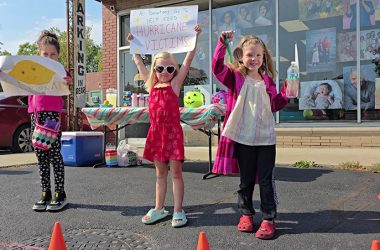 From left, Alba Thomas-Radovic, Charlie Guziejka and Elloren Thomas attempt to capture some attention for their cookies, juice and lemonade stand in front of Thomas Photographic Studio on Dixie Highway. (Eric Crump/H-F Chronicle)