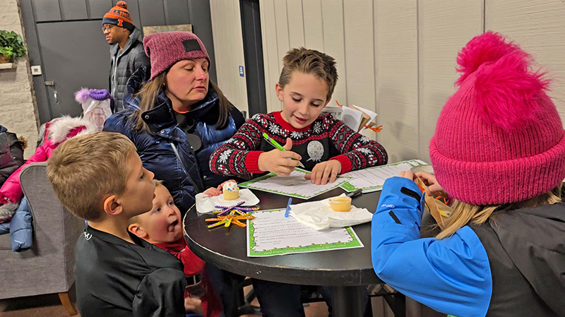 From left, Will and Charlie Otiola and Joanna King look on as Teddy King, center, and Dot King, right, work on letters to Santa at the Flossmoor holiday event Nov. 30. (Eric Crump/H-F Chronicle)