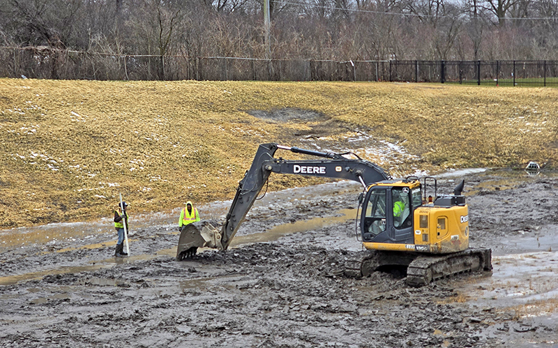 A crew works on fixing the grade at the bottom of the Heather Hill detention basin on Dec. 24. (Eric Crump/H-F Chronicle)