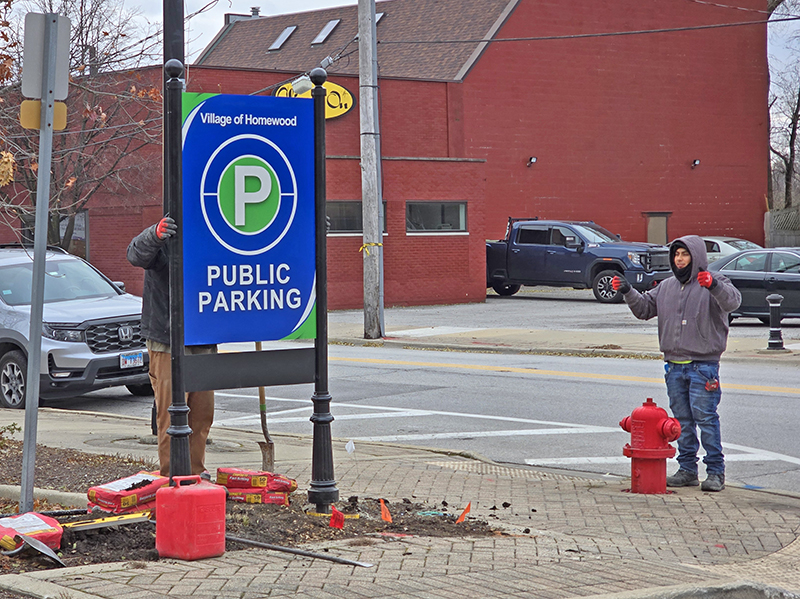 Workers from Roeda Signs install a new parking sign at Harwood Avenue and Kroner Lane on Dec. 4. Larger signs have been installed at lots around downtown in an effort to make it easier for people to find public parking. (Eric Crump/H-F Chronicle)
