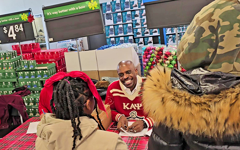 Derwin Phillip of Flossmoor greets a student who is checking in for the Chicago Heights Alumni Chapter of Kappa Alpha Psi Fraternity "Shopping with a Kappa" event at Walmart in Olympia Fields on Dec. 7. (Eric Crump/H-F Chronicle)