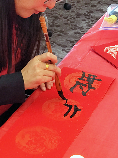 Yin Ding, a Mandarin teacher at Homewood-Flossmoor High School, writes a name in Mandarin. (Lolita Cusic/H-F Chronicle)