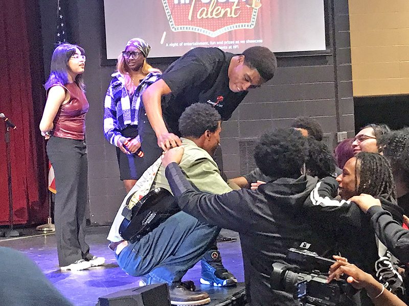 Jeremiah York, standing, and members of the audience, congratulate talent show winner Chaunto Drape as hosts Sommer Owens and Ashira Blakey look on. (Lolita M. Cusic/H-F Chronicle)