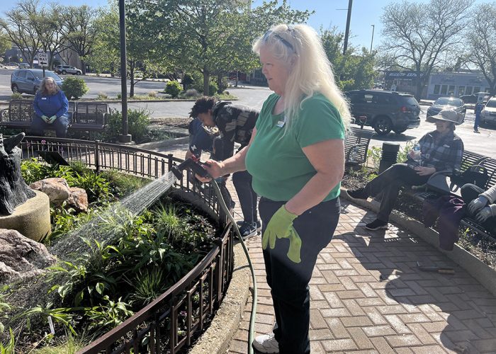 Homewood Public Library Director Colleen Waltman sprays the new flowers and prairie grass with a hose during the library's spring planting event on May 8. (Nick Ulanowski/H-F Chronicle)