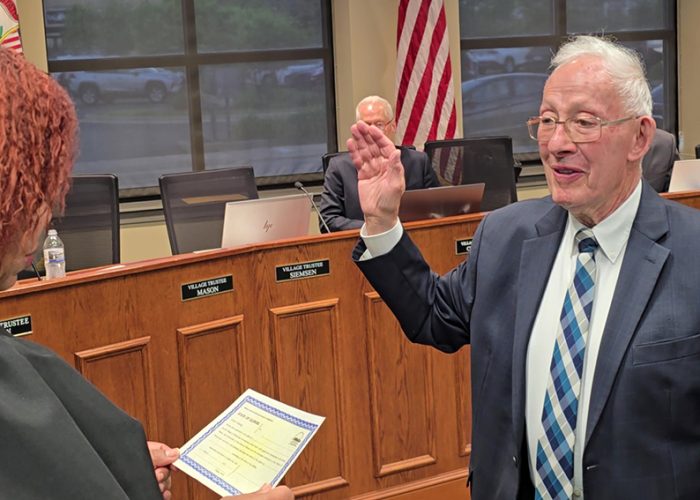 From left, Judge Barbara Dawkins administers the oath of office to Rich Hofeld, who is starting his eighth term as village president. (Eric Crump/H-F Chronicle)