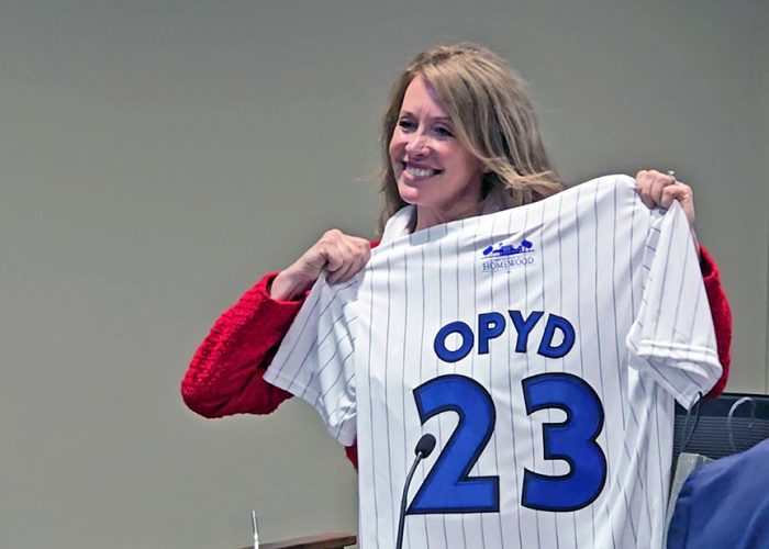 Allisa Opyd holds up a memento Homewood baseball jersey at her last meeting as village trustee on May 13. (Eric Crump/H-F Chronicle)