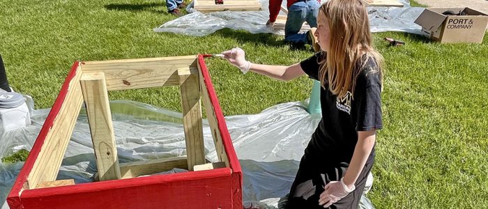 Aubree Kvasniska, who came from Chicago Heights to volunteer, paints a red pantry during the community build at Salem Lutheran Church. (Nuha Abdessalam/H-F Chronicle)