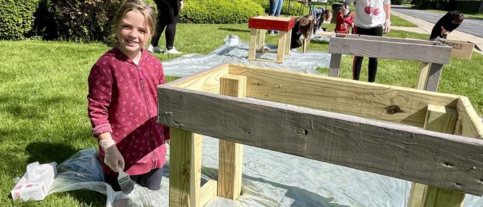 Eight-year-old Caty Fremouw beams beside the pantry she helped paint during the community build at Salem Lutheran Church. (Nuha Abdessalam/H-F Chronicle)