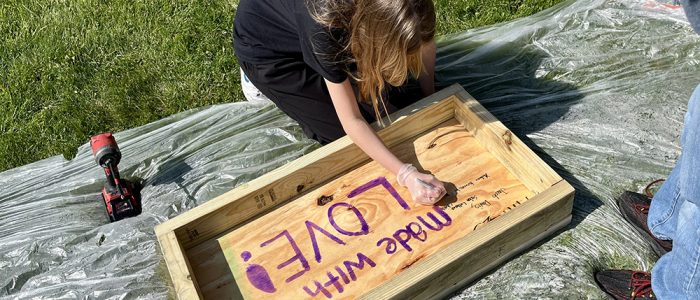 Gemma Davis signs her name on the bottom of a pantry box — a special touch encouraged by Korey Ziemkowski so every child could leave their mark on the project. (Nuha Abdessalam/H-F Chronicle)