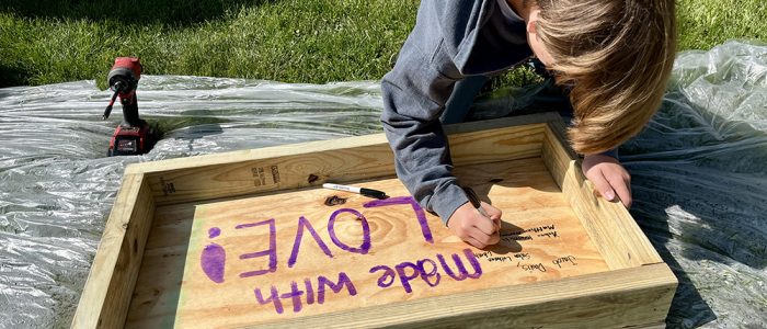 Matthew Fremouw signs his name to the pantry he helped build, a final step in the youth-led project at Salem Lutheran Church. (Nuha Abdessalam/H-F Chronicle)