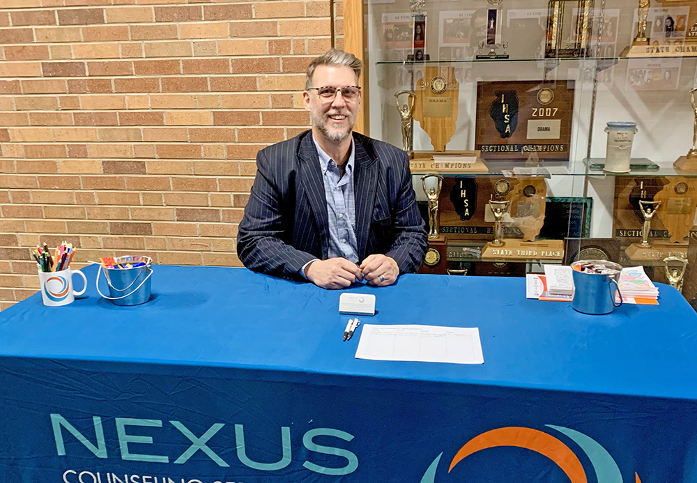 Therapist Kyle Miller of Nexus Counseling shares resources with attendees during Shatter the Silence at H-F. His booth featured local mental health services for teens and families. (Nuha Abdessalam/H-F Chronicle)
