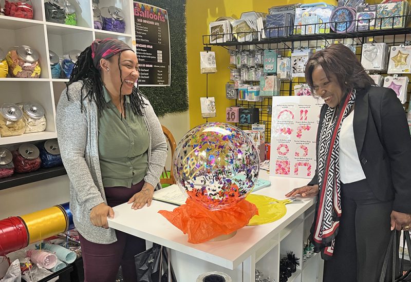 Illinois District Director of the U.S. Small Business Administration (SBA) Willette LeGrant, right, reacts to The Balloon Bar owner Javanah Barnes, left, giving her a custom balloon with the SBA logo during her walking tour of downtown Flossmoor. (Nick Ulanowski/H-F Chronicle)