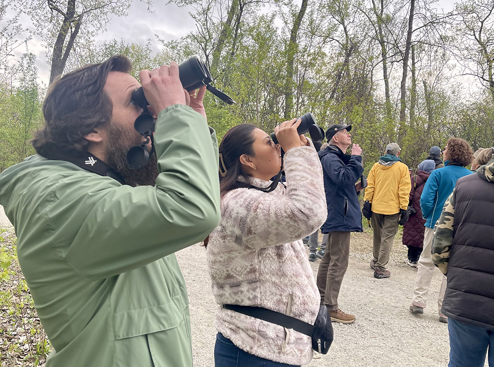 World Migratory Bird Day attendees at Izaak Walton Preserve use binoculars to scan for birds during a tour. (Summer Kiswani/ H-F Chronicle)