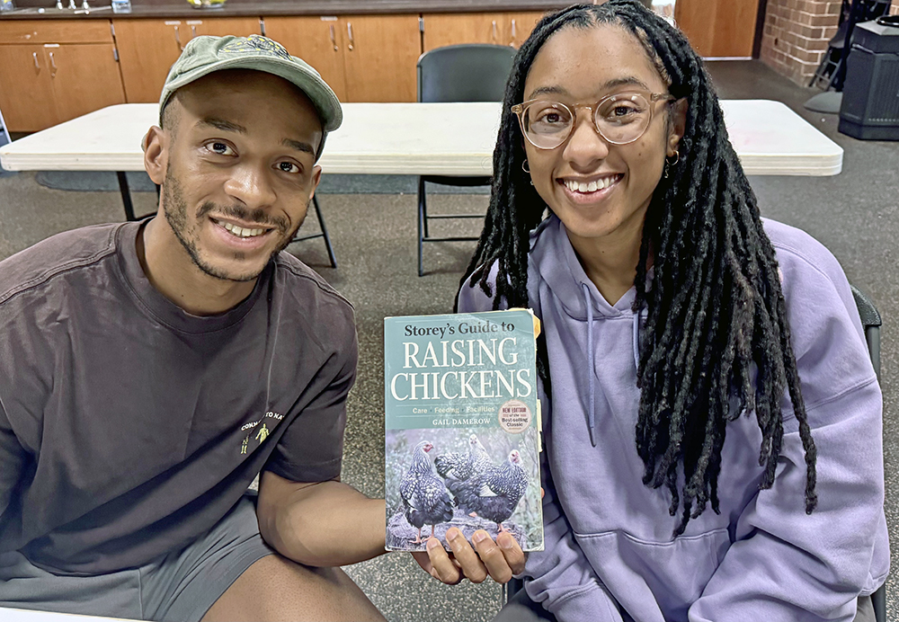 Homewood residents Wes Blakely, left, and Dillon Lively display a book Jennifer Murtoff recommends for anyone interested in chicken-keeping — “Storey’s Guide to Raising Chickens” by Gail Damerow. (Karen Torme Olson/H-F Chronicle)