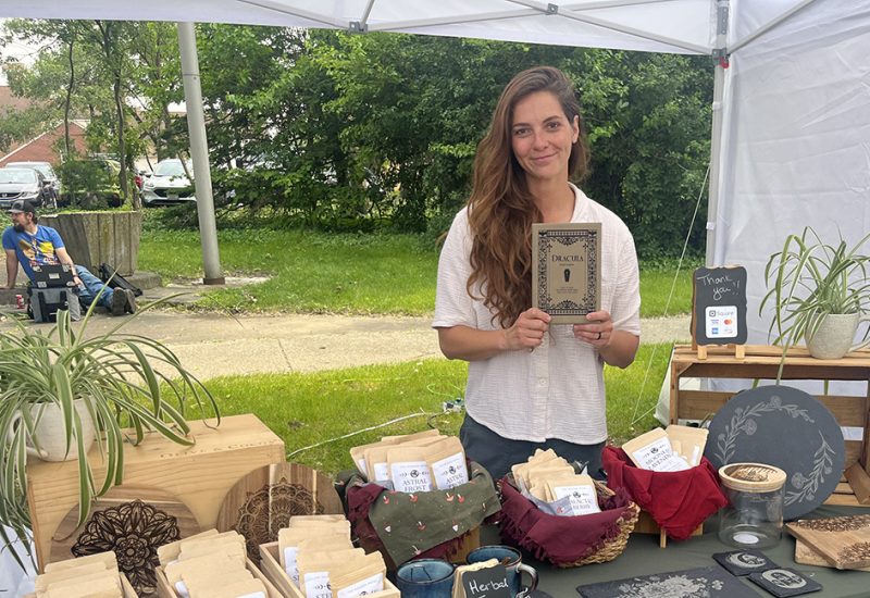 Sarah Rivers Armstrong, a Homewood resident and the Wooden Petal owner, holds up a leatherette journal with a Dracula cover at Homewood Art & Garden Fair. (Nick Ulanowski/H-F Chronicle)