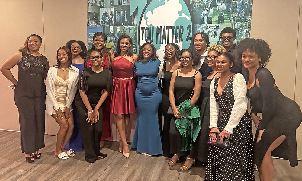 Destiny Watson, middle in blue dress,, CEO and founder of You Matter 2, celebrates with organization alumni impacted by the nonprofit’s programs. (Faith Lee/H-F Chronicle)