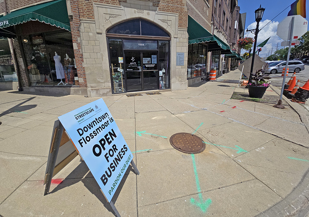 A sign at the corner of Flossmoor and Sterling roads reminds visitors that downtown shops will remain open during the streetscape construction work this summer. The village built requirements in the contract to ensure business disruption would be kept to a minimum. (Eric Crump/H-F Chronicle)