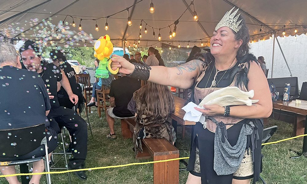 Rabid Brewing co-owner Raiye Rosado blows bubbles into the crowd with a bubble-making device during the Feast of the Goat Queen on July 26. (Nick Ulanowski / H-F Chronicle)