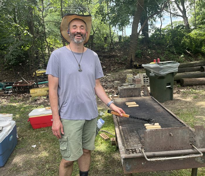Izaak Walton volunteer Lorenzo Pesce grills hot dogs for community members at the July 4 picnic. (Nick Ulanowski / H-F Chronicle)